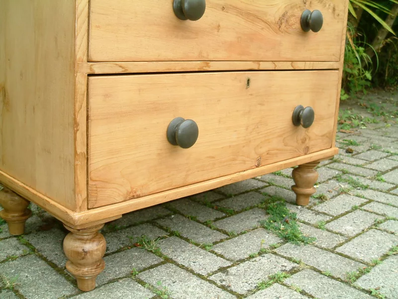 Image of the base of the antique pine chest, showig the turned feet