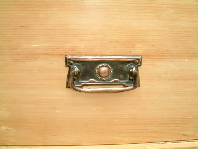 Close image of the bronzed plate handle on the vintage pine chest of drawers