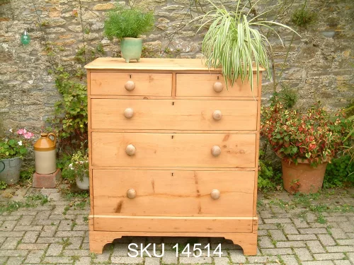 Front image of the antique pine chest of drawers with plants for decoration
