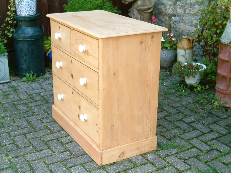Image of the right side of the antique pine chest of drawers, showing the side plinth